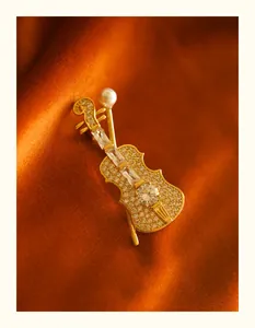 Close-up of elegant gold violin brooch with rhinestones and pearl on velvet background