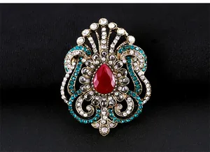 Vue détaillée d'une broche baroque vintage avec cristal rouge et strass bleu-vert