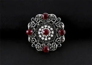 Gros plan d'une broche de style baroque vintage avec cristaux rouges et ferronnerie