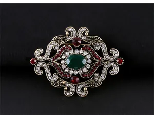 Vue détaillée d'une broche baroque vintage de qualité avec cristaux vert émeraude et rouges
