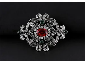 Vue détaillée d'une broche en argent vintage de style baroque avec un grand cristal rouge