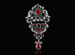 Gros plan d'une broche baroque vintage avec cristaux rouges et verts sur fond noir