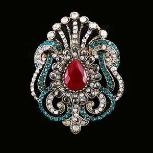 Broche vintage de style baroque élégante avec pierre centrale rouge et cristaux verts
