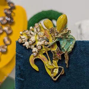 Nahaufnahme einer Vintage-Emaille-Feen-Brosche mit Blumen und Kristallstern auf blauem Samt.