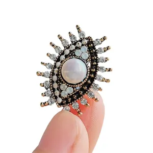 Vintage boze oog broche met zoetwaterparel en sprankelende strassteentjes op wit