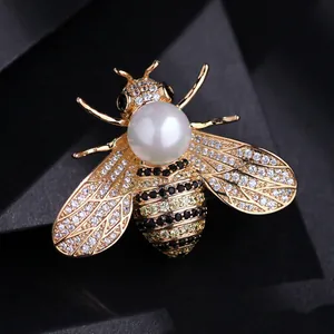 Elegant gold bee brooch pin with large white pearl and crystal wings on black background