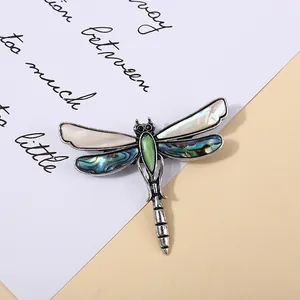 Macro view of a vintage dragonfly brooch featuring iridescent abalone shell inlays