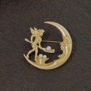 Detailed view of a vintage gold baroque moon and angel brooch with white pearls.