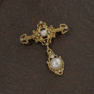 Close-up of vintage baroque gold brooch with elegant pearl dangles and crystals
