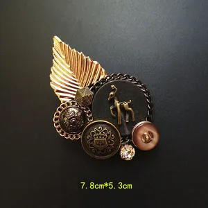 Primer plano detallado de un broche emblema barroco con medida 7,8 cm por 5,3 cm.