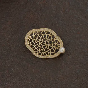 Elegant vintage gold hollow brooch featuring pearls and crystals on a dark stone base