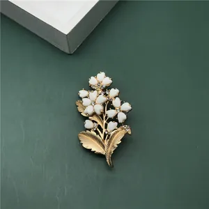 Detailed view of elegant baroque gold flower brooch with white enamel petals