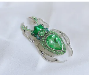Macro detail of a vintage insect brooch featuring green crystals and enamel work