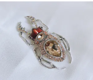 Close-up of vintage beetle brooch featuring sparkling champagne crystals and enamel detail.