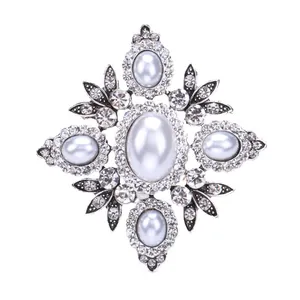 Vintage barokke parel kruis broche met fonkelende strass op een witte achtergrond