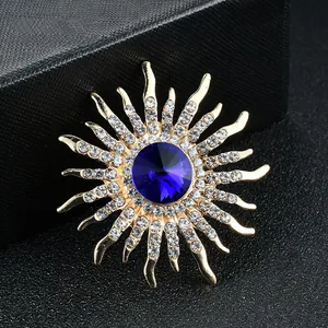 Detailed view of sun-burst brooch with deep blue center crystal and clear rhinestones