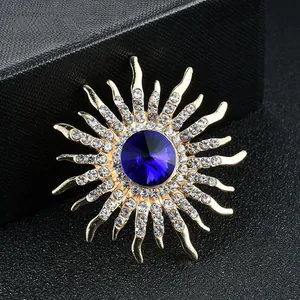 Elegant sunburst crystal brooch with large blue center stone and gold-toned finish