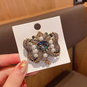 Primer plano de broche de mariposa vintage con cristales brillantes y perlas finas