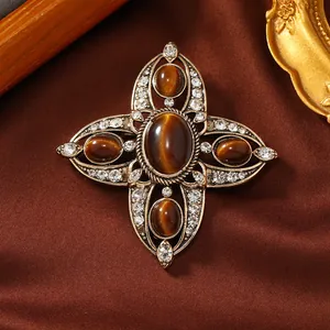 Detail-Nahaufnahme einer antiken hohlen Kreuzbrosche mit braunen Steinen und Strass