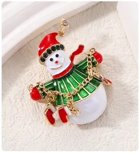 Vue détaillée d'une broche bonhomme de neige de Noël avec émail rouge et breloques