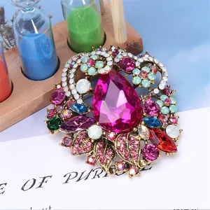 Detail van een vintage Boheemse broche met een grote roze druppelstrass en goud filigraan.