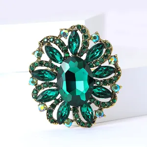 Close-up of a vintage emerald green crystal flower brooch with antique gold alloy finish