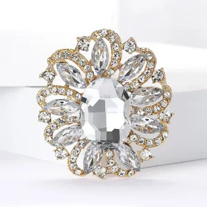 Detailed macro view of a luxury vintage flower brooch with clear rhinestones and gold plating.