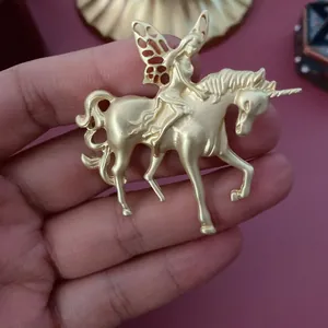 Vue détaillée d'une broche vintage en or mat représentant une fée sur un licorne.