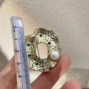 Vue détaillée montrant la taille d'une broche baroque dorée irrégulière avec perle