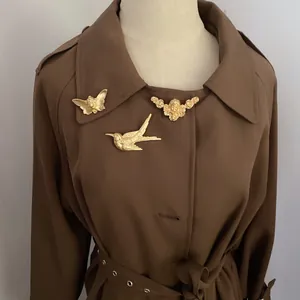 Détail de broches vintage en or mat aux motifs d'oiseau, de papillon et d'ange