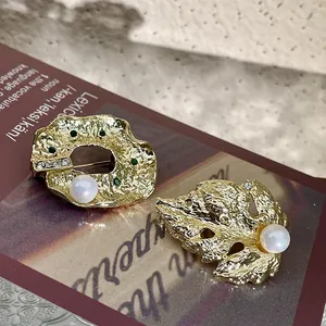 Vue détaillée de magnifiques broches baroques dorées en forme de feuille et perles