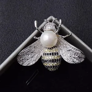 Close-up of a sparkling bee brooch featuring pavé crystals and a central white pearl