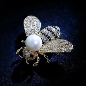 Detailed view of an elegant gold-plated insect bee brooch with pearl and zircons