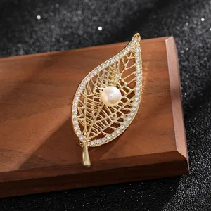 Detailed view of an elegant gold leaf brooch with rhinestones and a central pearl