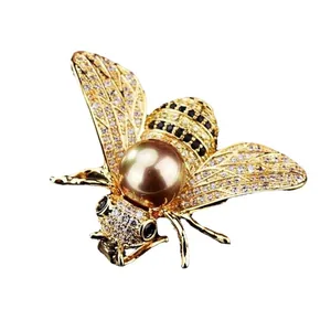 Elegant gold-toned bee brooch featuring zircon wings and a champagne pearl center
