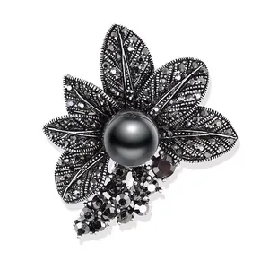 Detailansicht einer Vintage-Blumenbrosche mit großer schwarzer Perle und dunklen Strasssteinen.