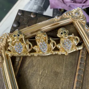Vista dettagliata della spilla vintage dorata con tre scimmie sagge e intarsio di strass