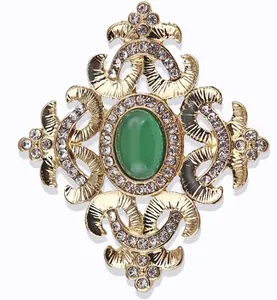 Close-up of vintage baroque brooch with green stone and sparkling rhinestones