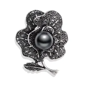 Detaillierte Ansicht einer Vintage-Blumenbrosche mit schwarzer Perle und dunklen Strasssteinen