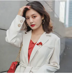 Elegant red crystal flower basket brooch pinned on a stylish white blazer lapel