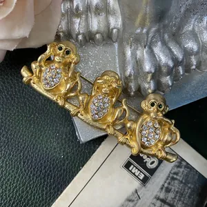 Vista macro dettagliata della spilla vintage placcata oro con tre scimmie e strass cechi