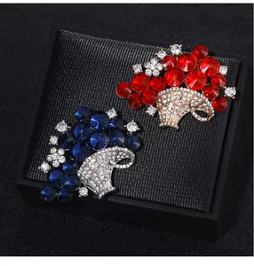 Detailed view of red and blue crystal flower basket brooches on a black display box