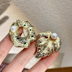 Gros plan détaillé de broches baroques dorées avec perles en forme de feuille