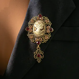 Gros plan détaillé d'une broche camée vintage avec cristaux rouges sur un veston.