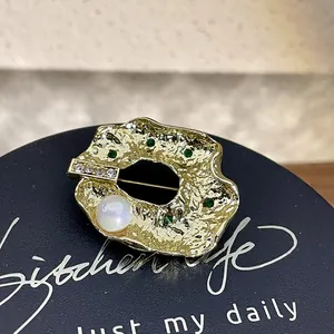Gros plan sur une broche baroque dorée avec perle élégante et pierres précieuses vertes