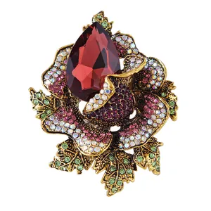 Ornate luxury rose crystal brooch featuring a large red teardrop faceted gemstone