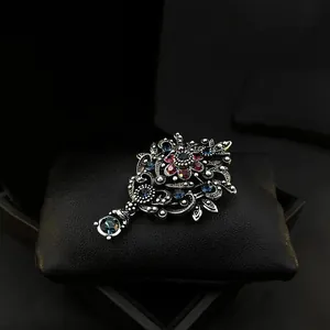 Vintage palace style crown brooch with red and blue rhinestones on black cushion.