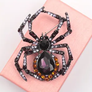 Macro view of vintage spider brooch with purple and amber crystals on a pink jewelry box