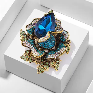 Close-up of luxury flower brooch with large blue teardrop crystal and pavé settings