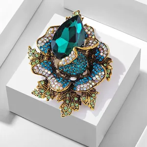 Detail showing luxury emerald green crystal rose brooch on white geometric display